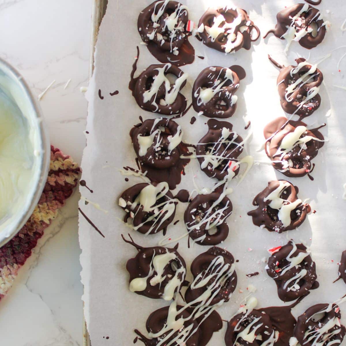 Drizzle melted white chocolate over lightly set chocolate dipped pretzels.