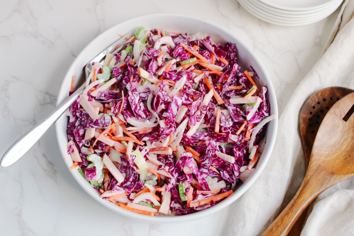 red cabbage salad on plate with tongs on side