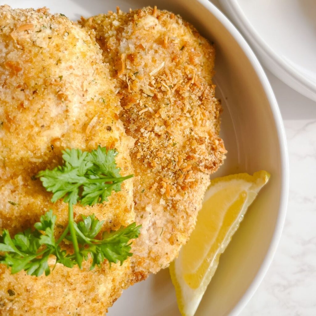 Garnish the fried chicken with fresh parsley and a lemon slice.