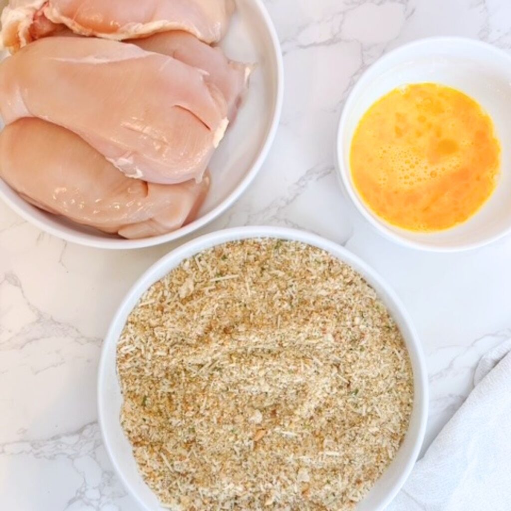 In 3 separate bowls put the chicken breast, whisked egg mixture and sourdough breadcrumb mixture.
