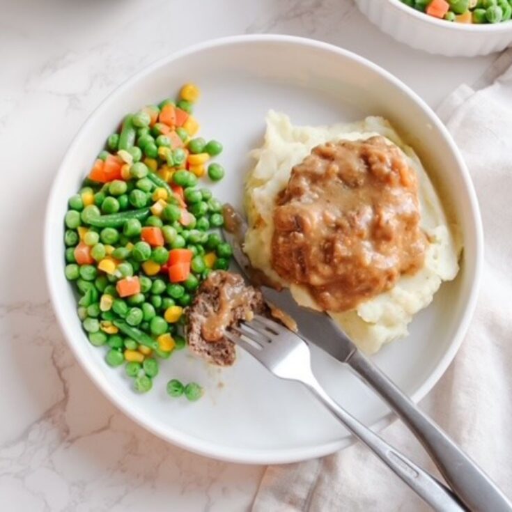 Salisbury steak served with mixed veggies and mashed potatoes