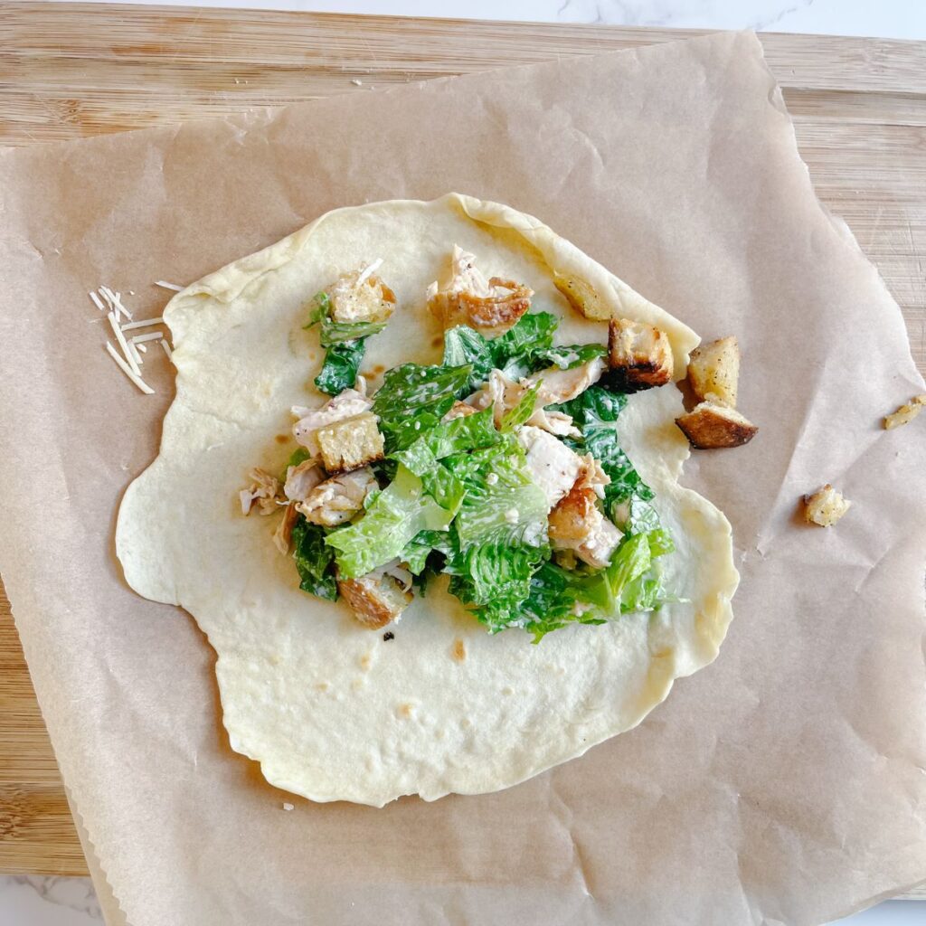 Add the chicken caesar salad mixture into the tortilla to create the chicken caesar sandwich wrap.
