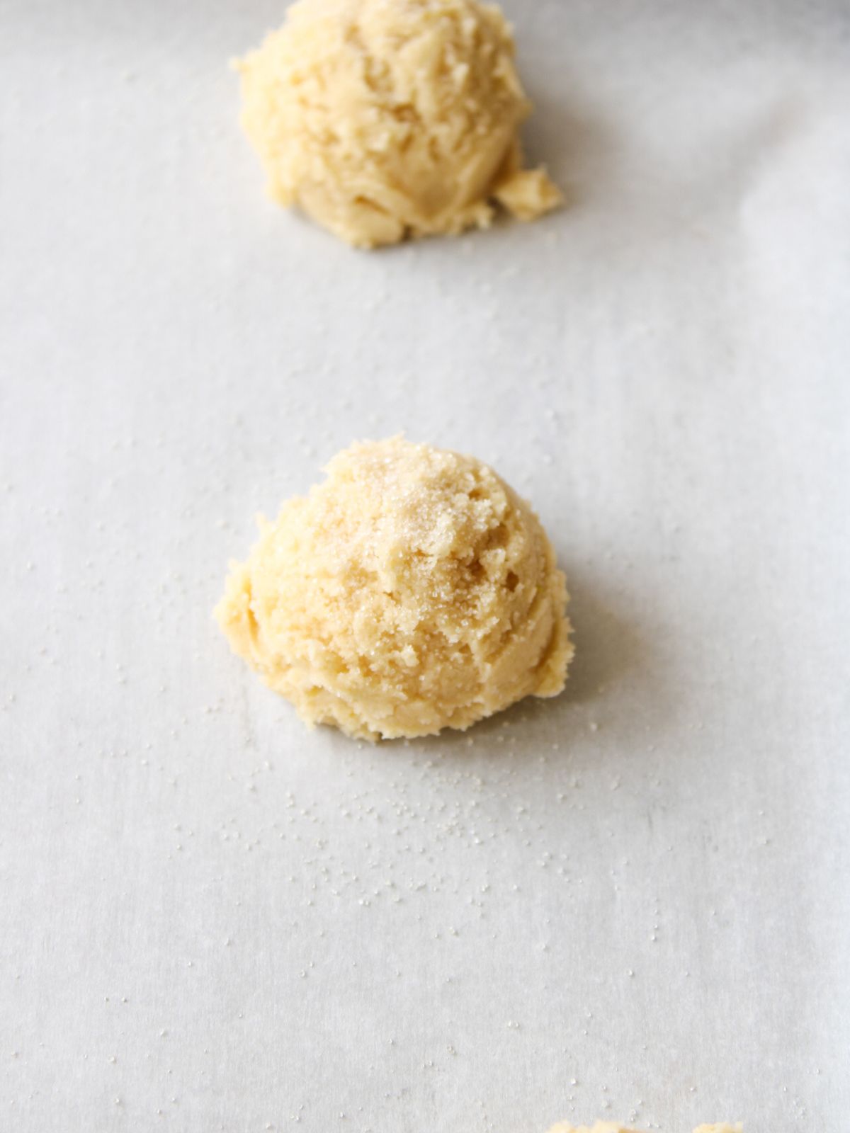 Sprinkle the top of the unbaked cookie dough ball with granulated sugar.