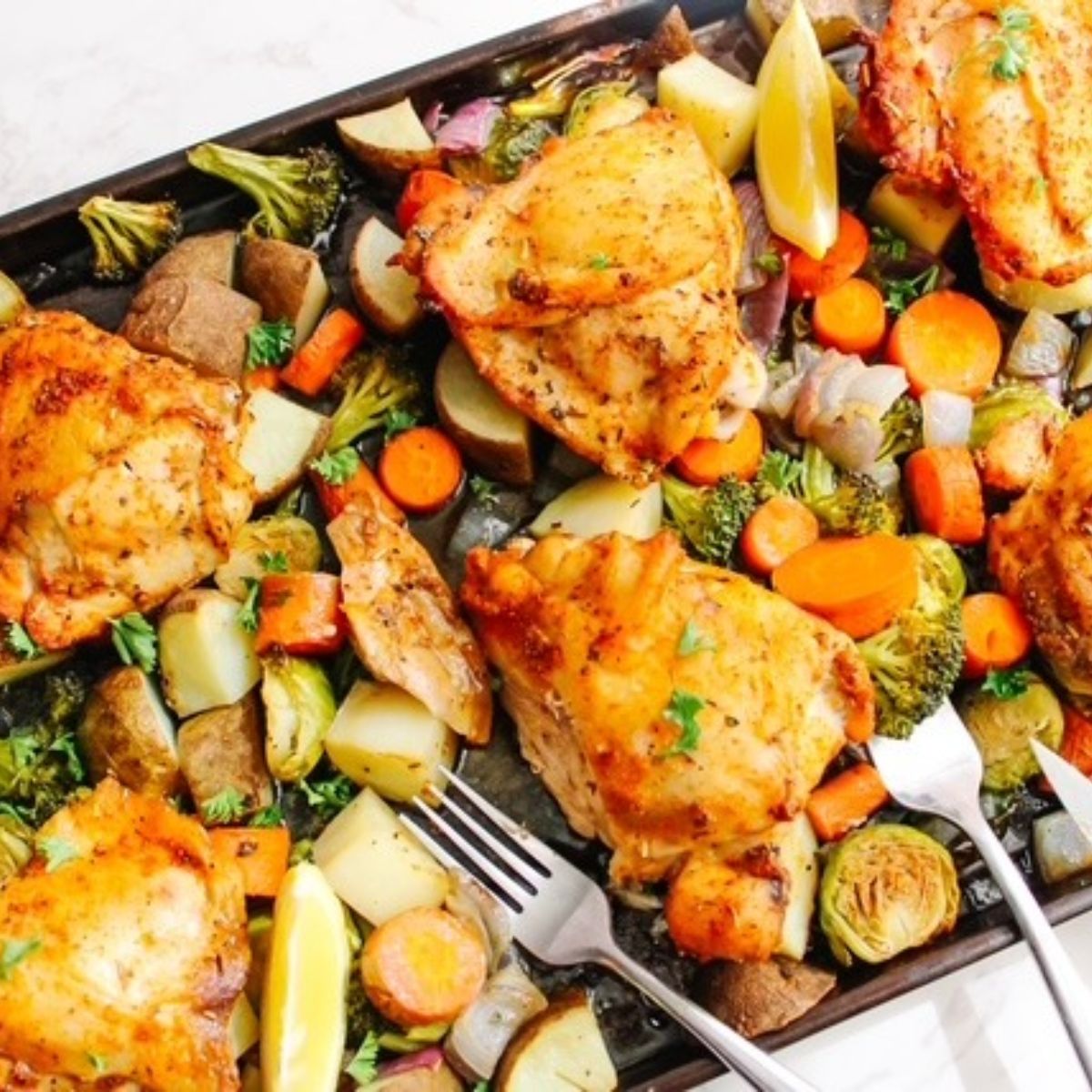 baked chicken and veggies with forks