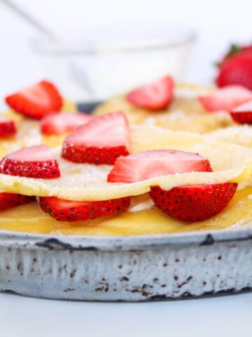 A close up of a sourdough discard crepe with fresh strawberry slices.