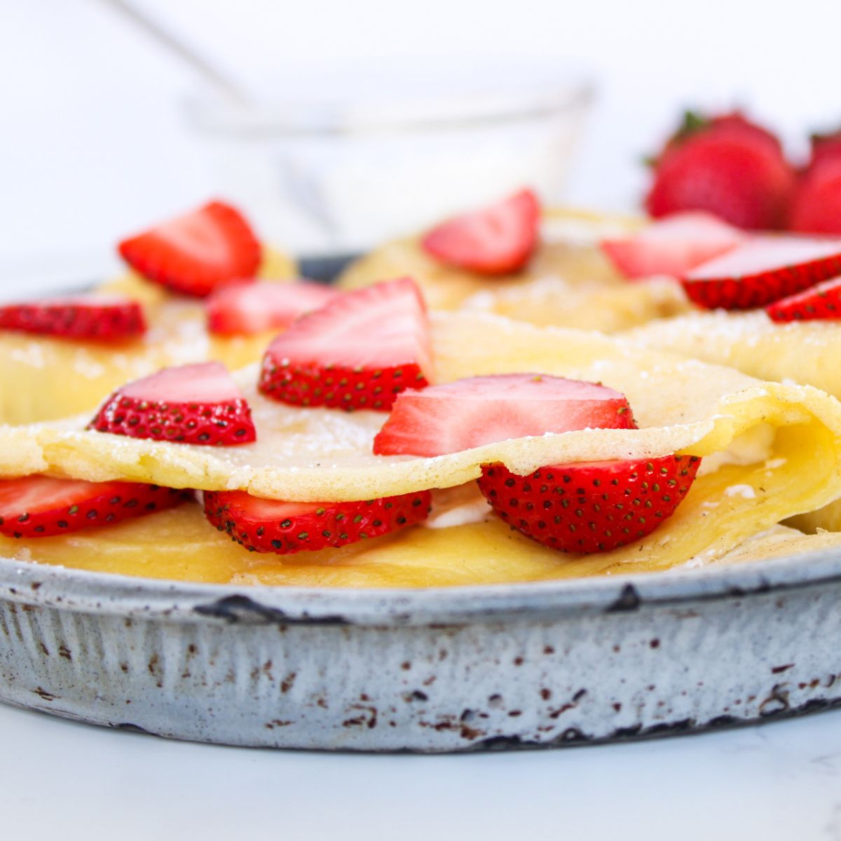 A close up of a sourdough discard crepe with fresh strawberry slices.