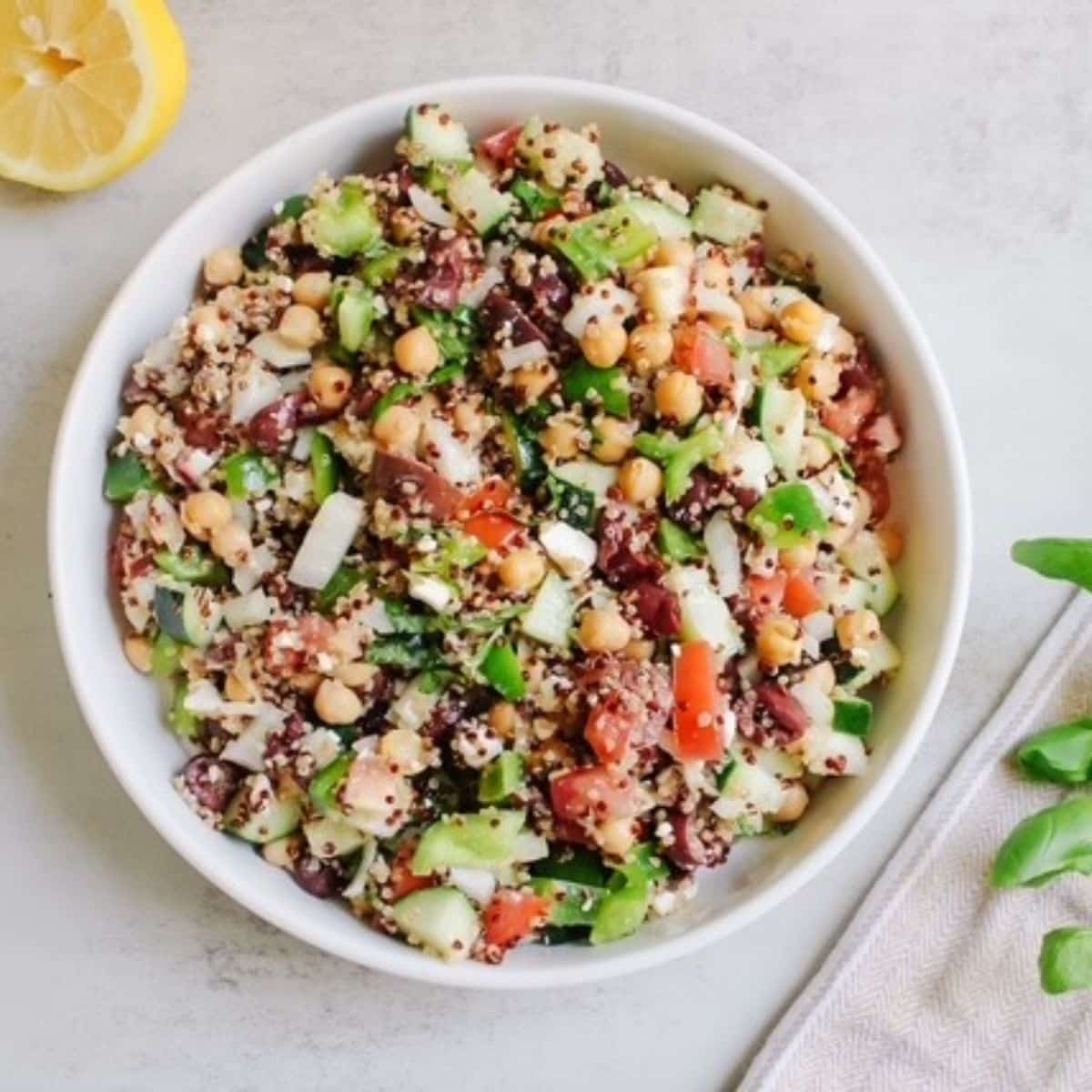 A white bowl full of cucumber quinoa tomato salad