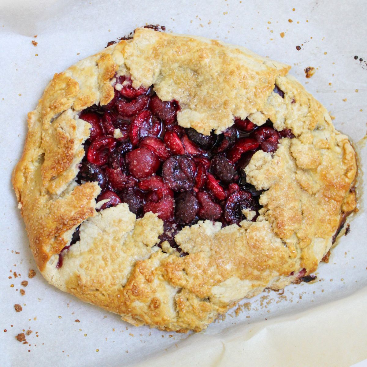 A cherry galette on a baking sheet lined with parchment paper.