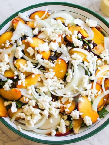 A salad bowl filled with a goat cheese peach salad.