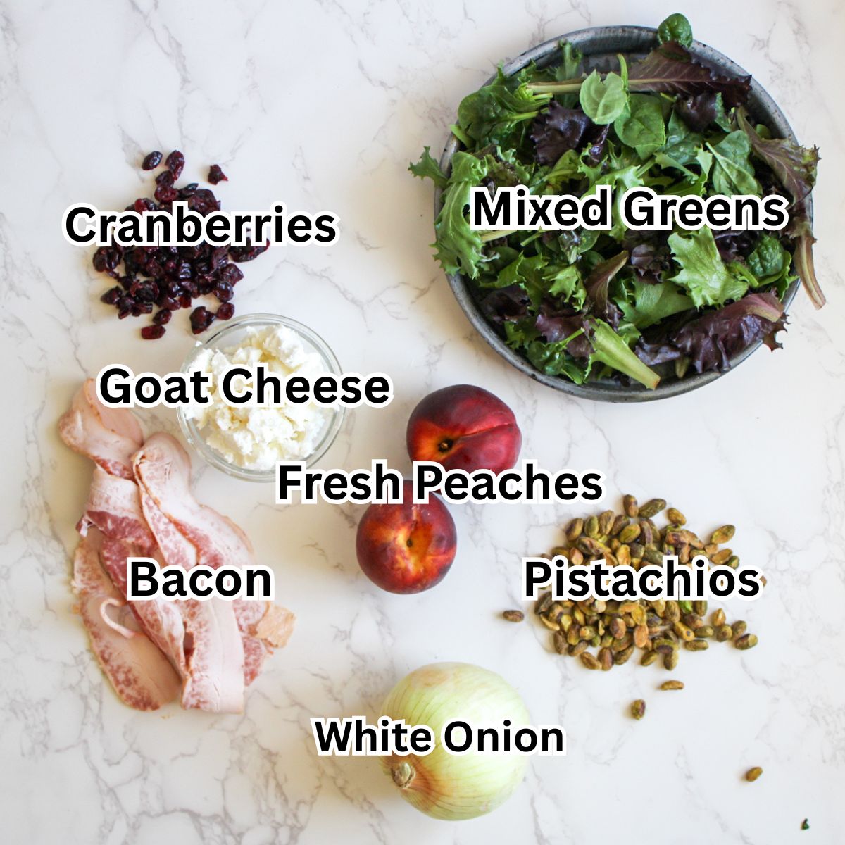 Ingredients for a goat cheese peach salad-mixed greens, cranberries, goat cheese, fresh peaches, pistachios, bacon and white onion.