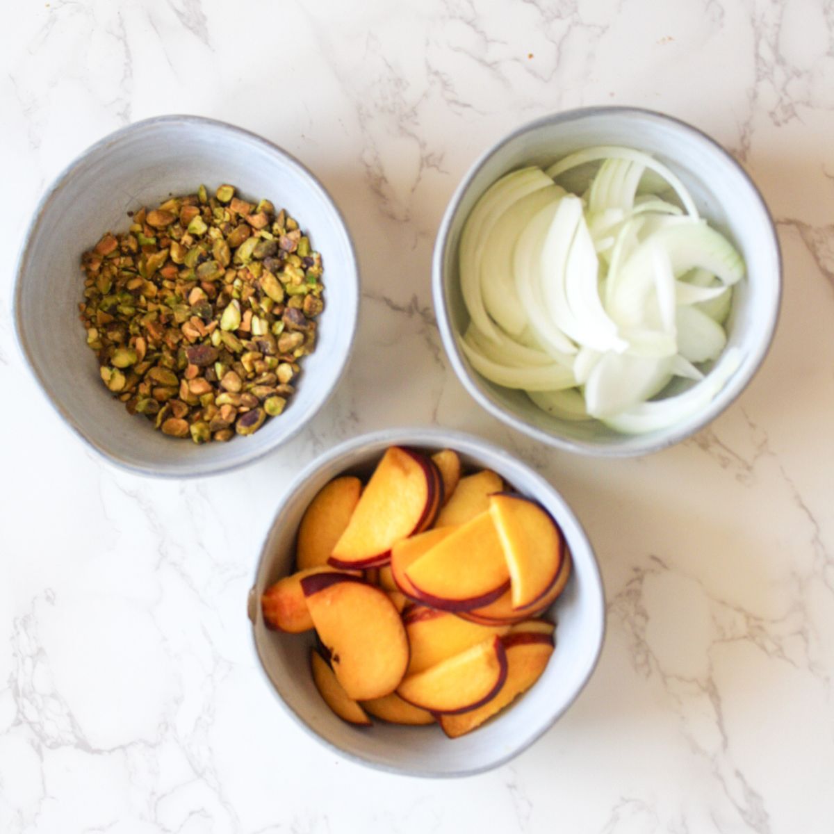 Roughly chop the pistachios and slice the white onions and fresh peaches.