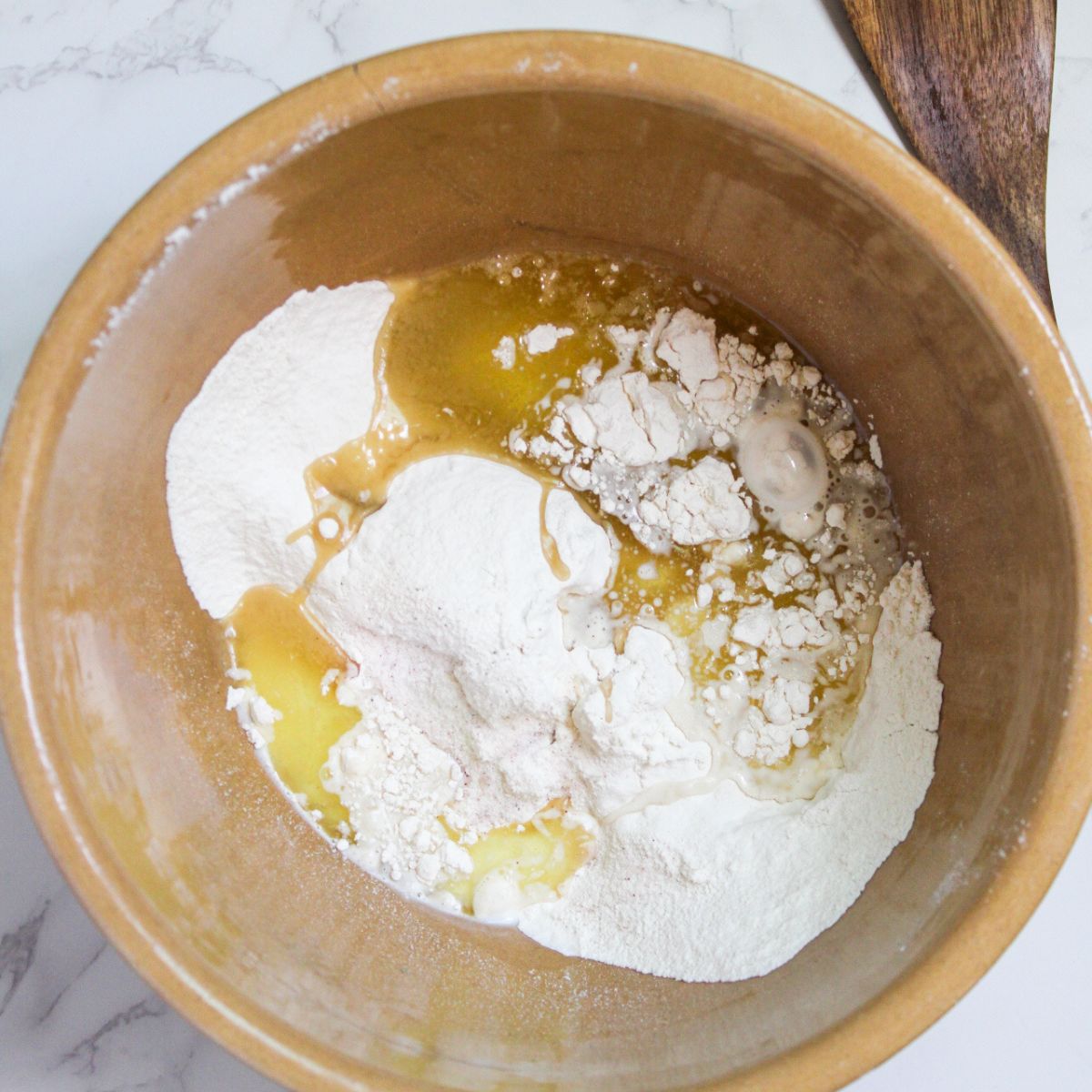 A large mixing bowl with oil, eggs and flour