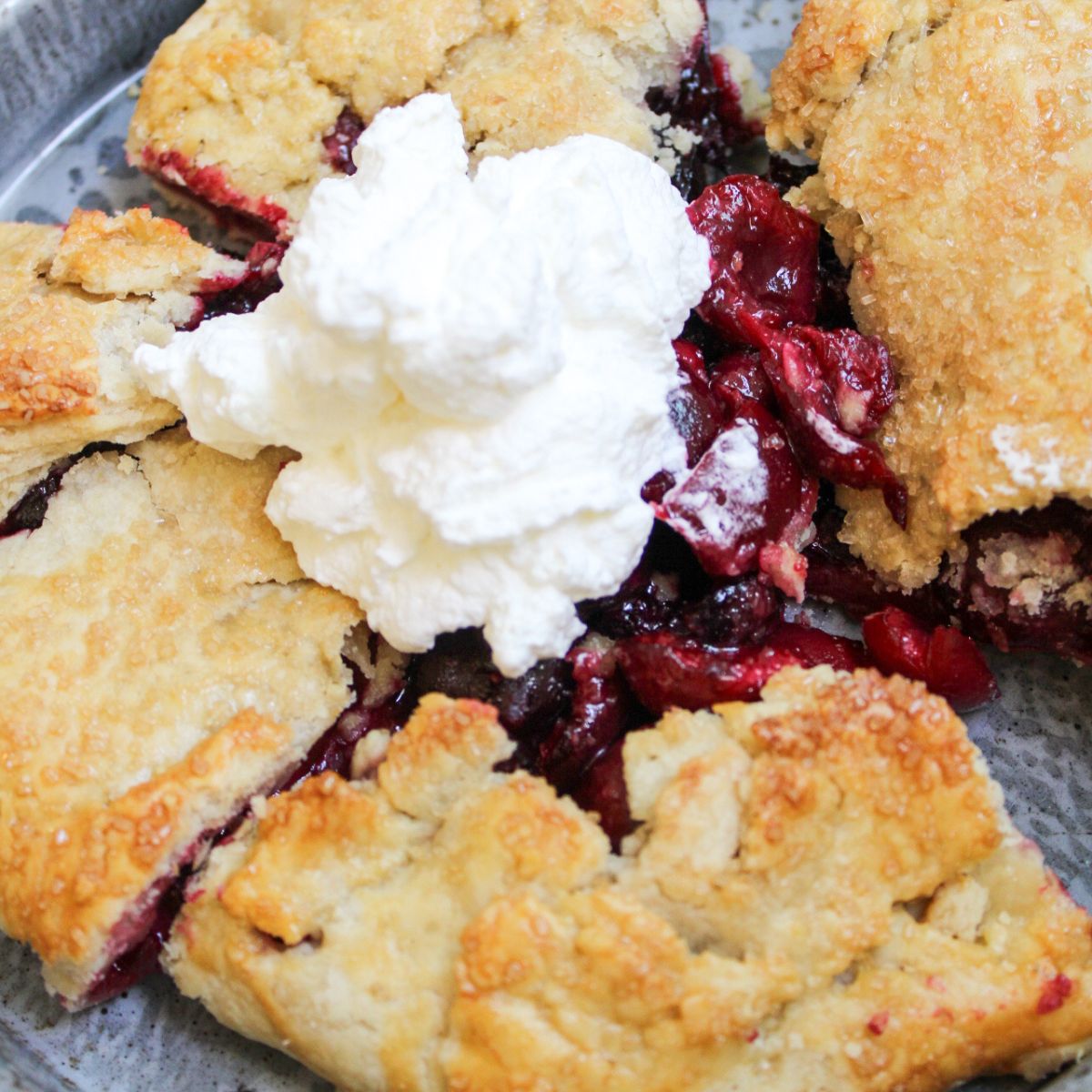 A cherry galette topped with homemade whipped cream.