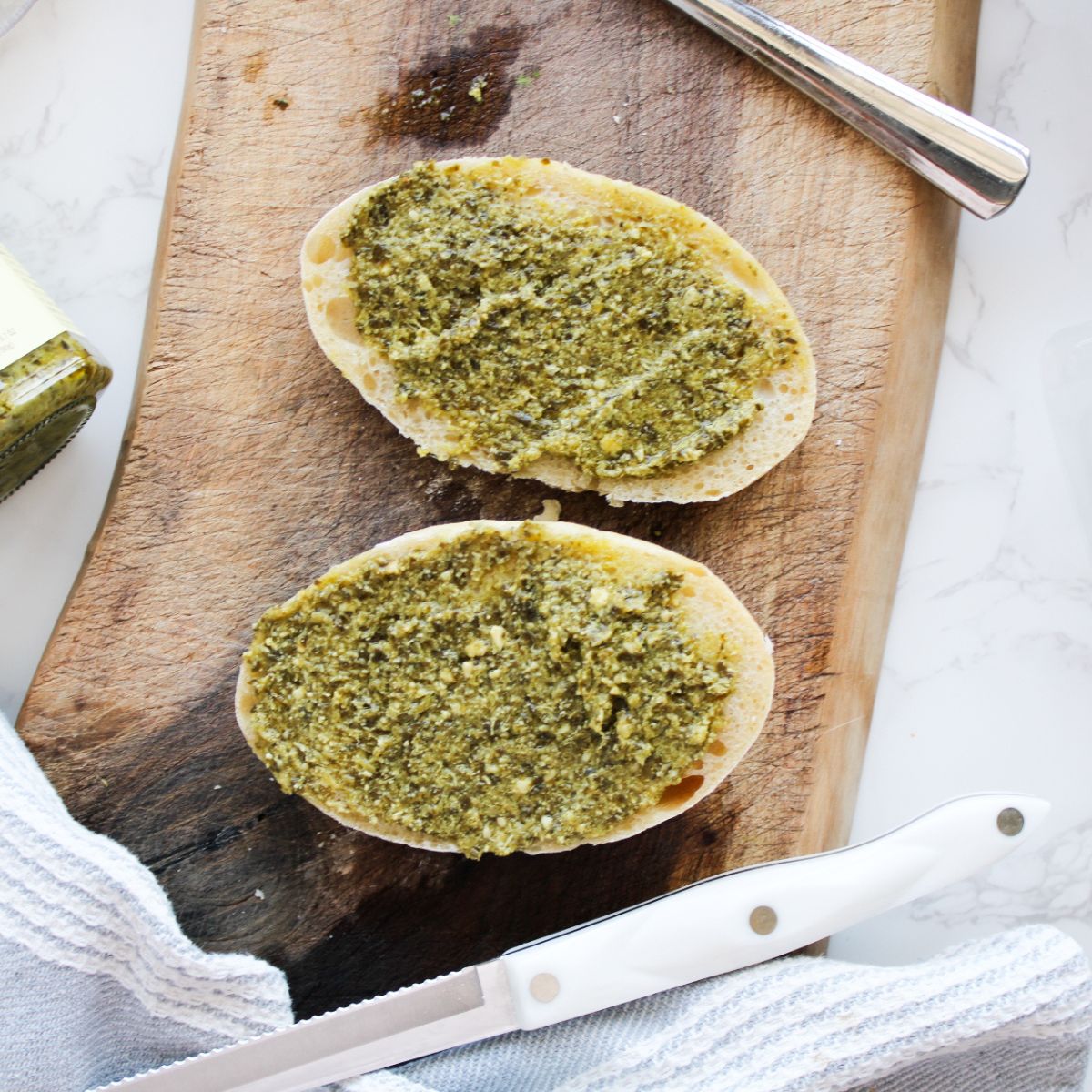Spread pesto on both halves of the panini bread.