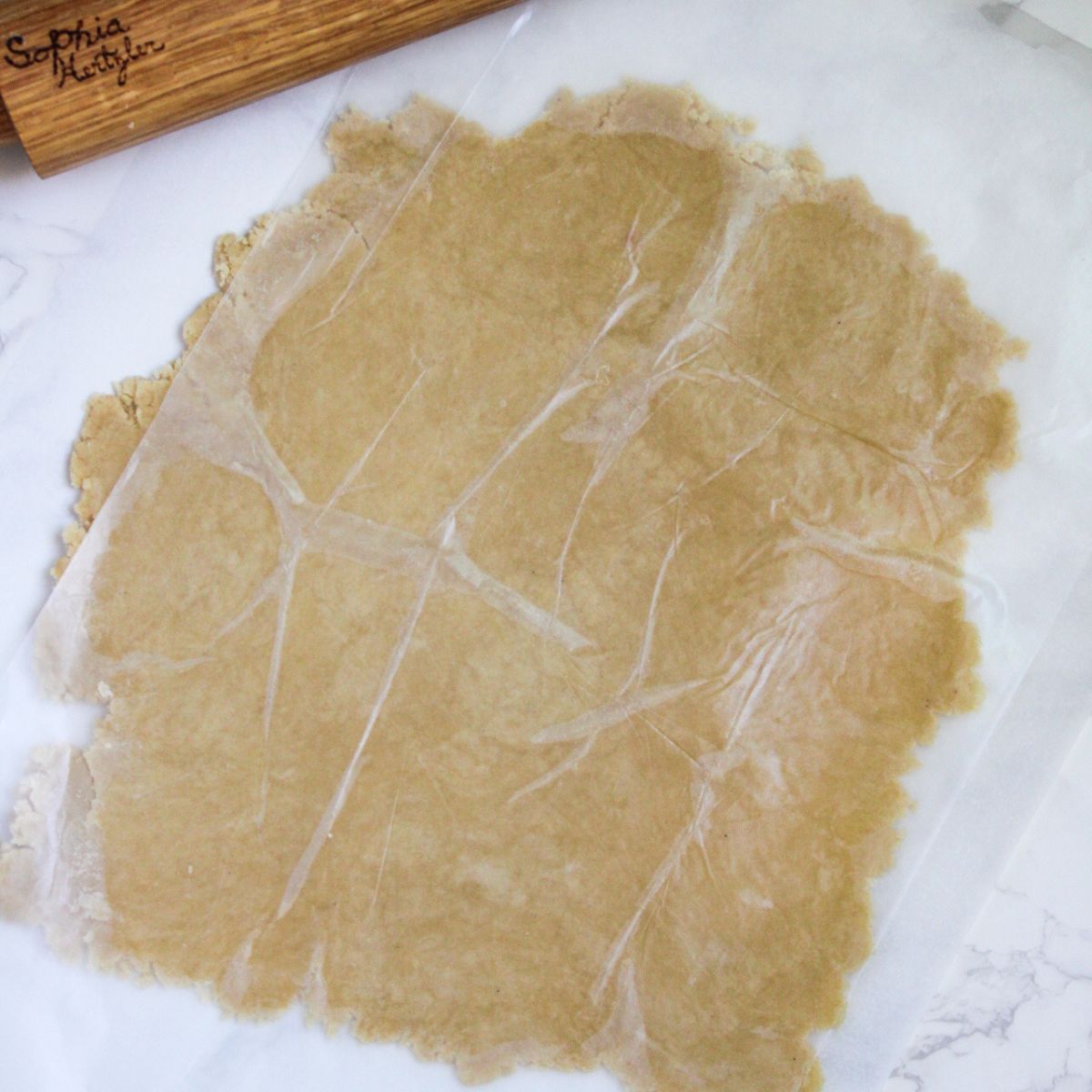 Roll out the pie crust under a piece of wax paper into a rough circle shape.