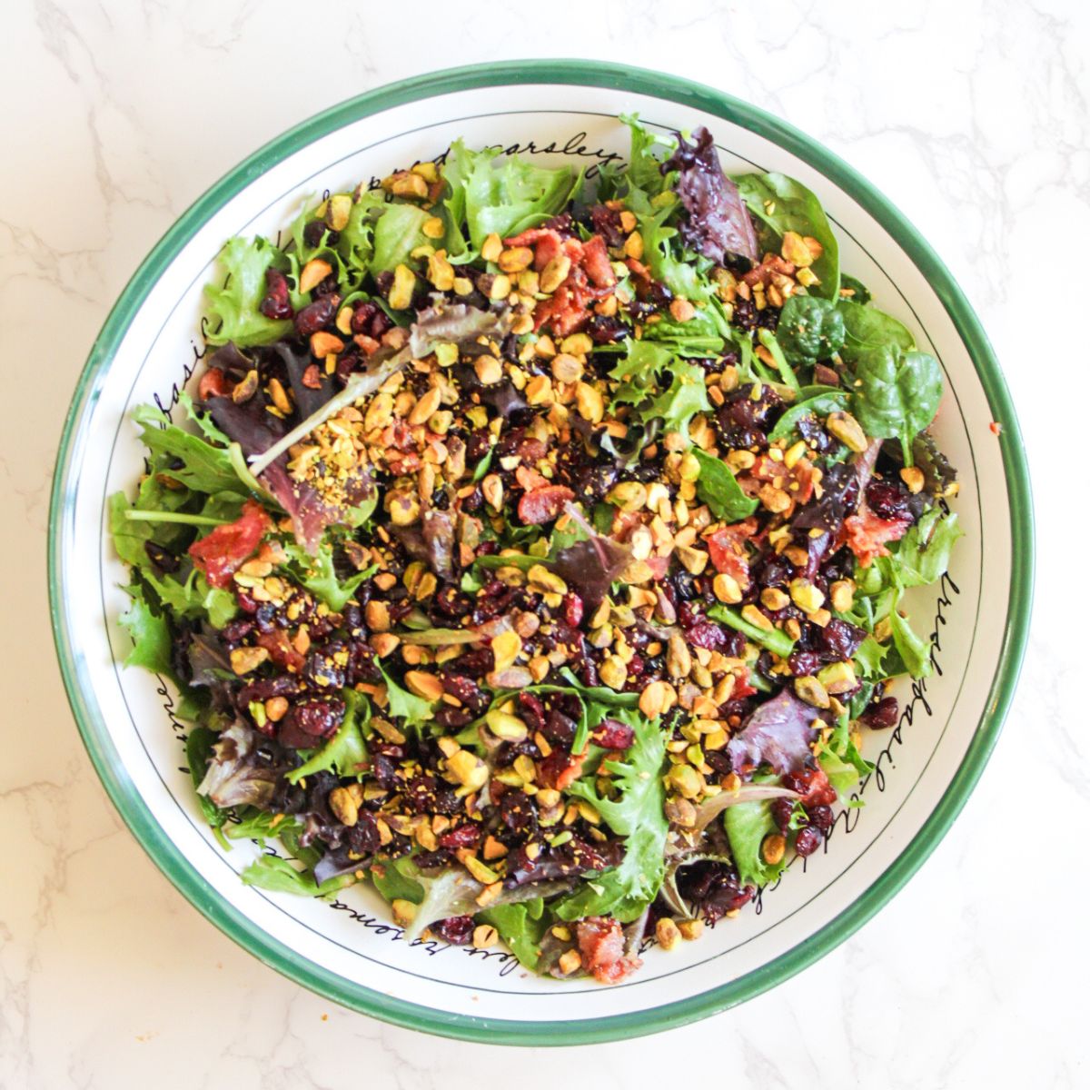 Top the salad with pistachios, cranberries and bacon.
