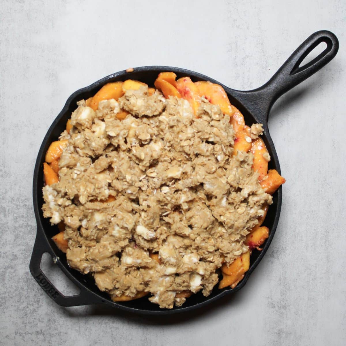 Unbaked peach crisp in a cast iron skillet