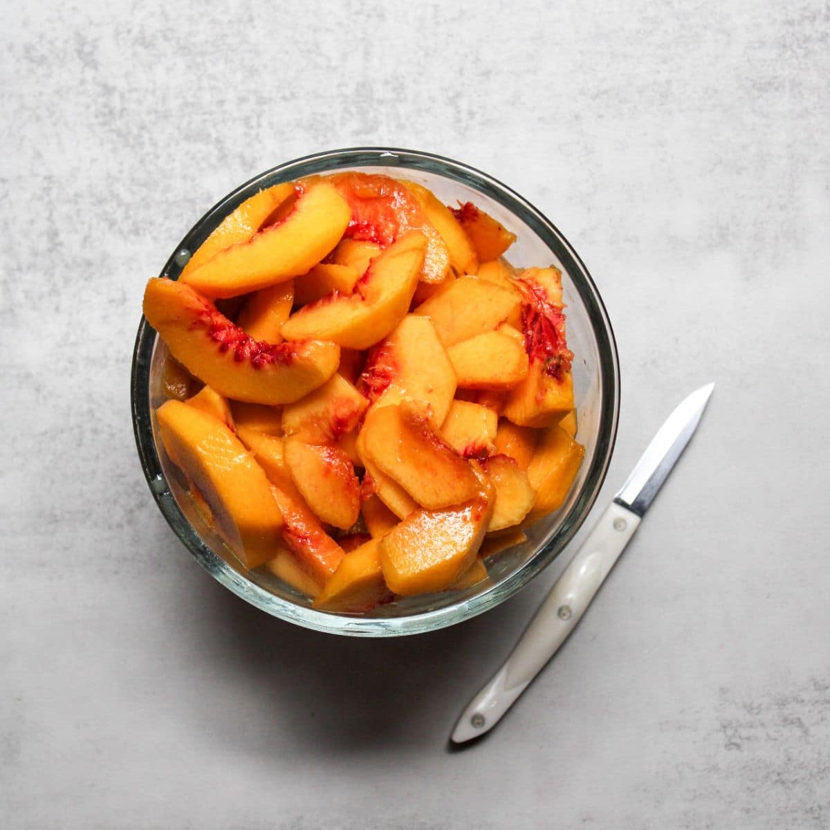 Slice the fresh peaches into a bowl.