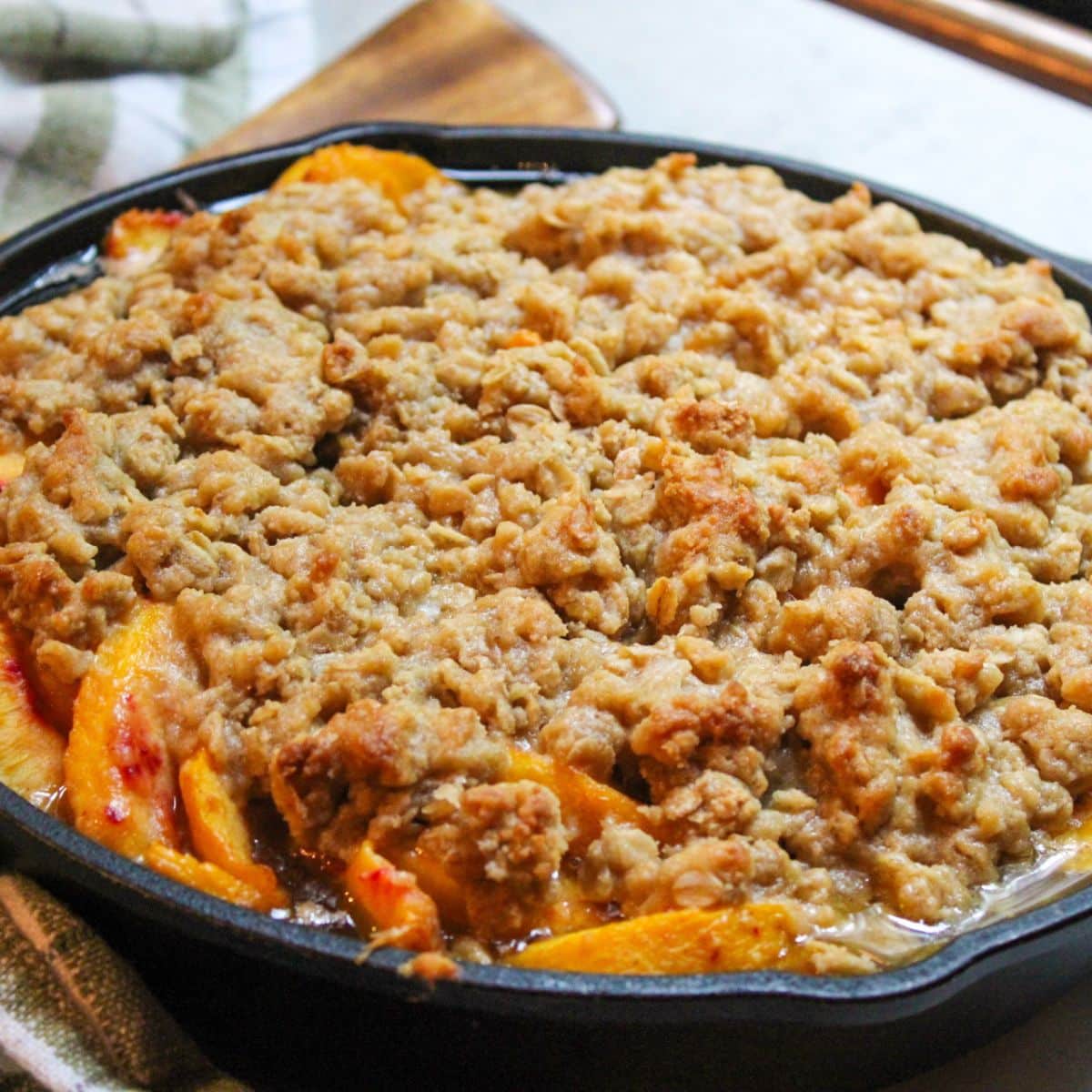 Golden brown peach crisp in a cast iron skillet.