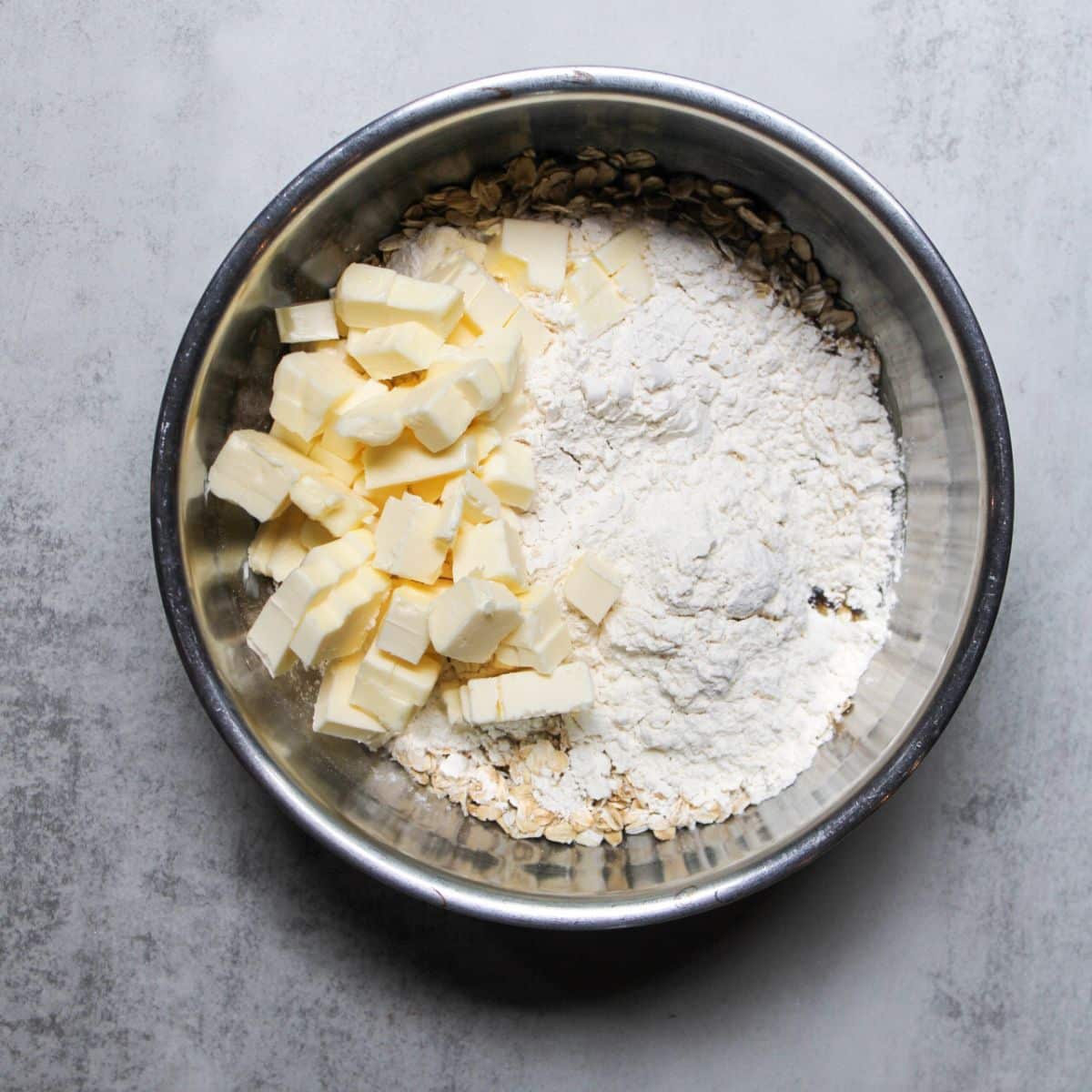 Butter, flour, and oats in a silver mixing bowl.