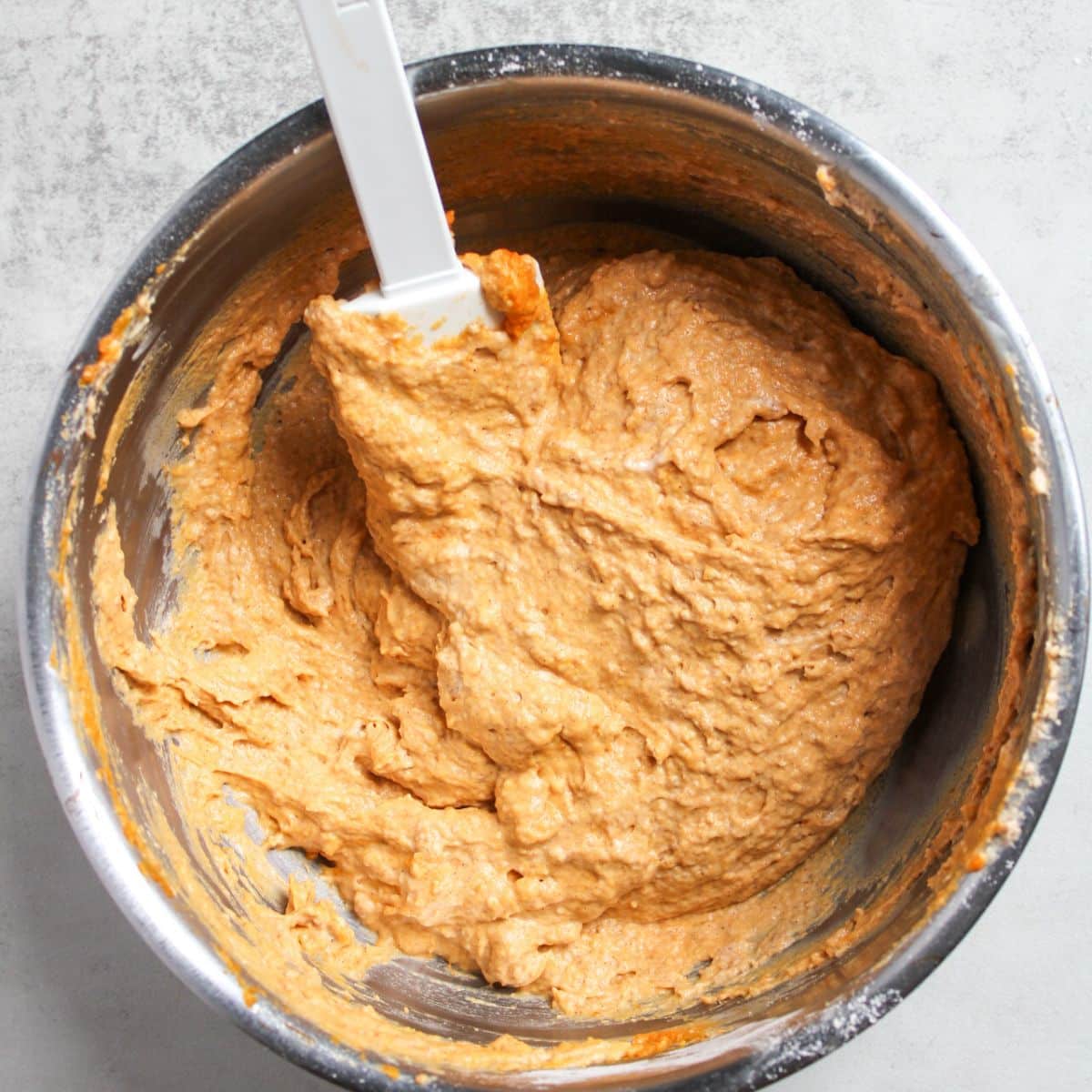 Orange colored sourdough pumpkin pancake batter in a large mixing bowl