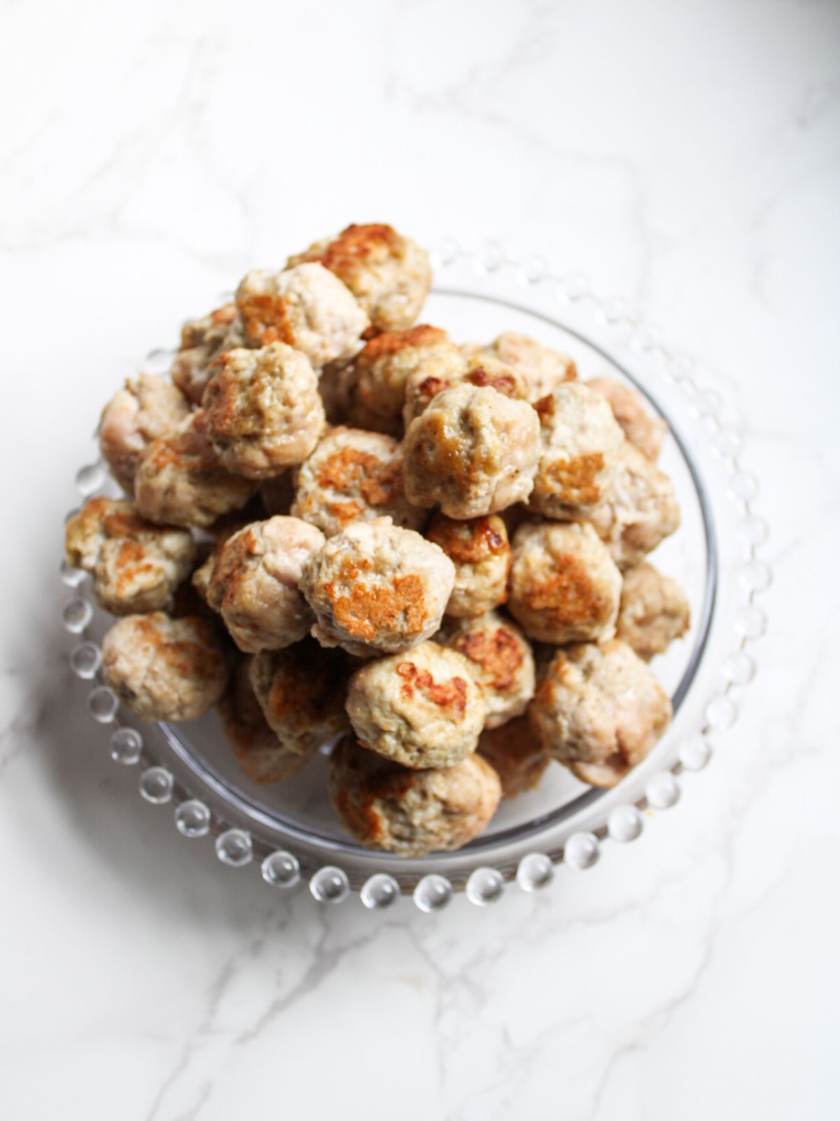 A glass plate filled with a pile of mini meatballs.