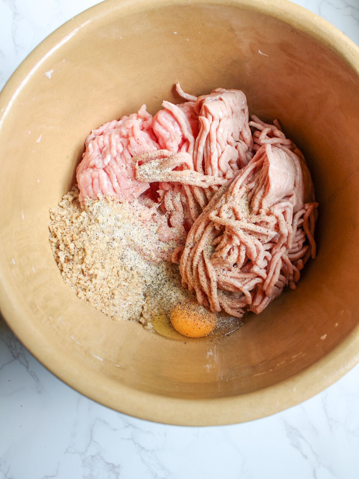 Ground turkey, ground pork, breadcrumbs and one egg in a large mixing bowl.