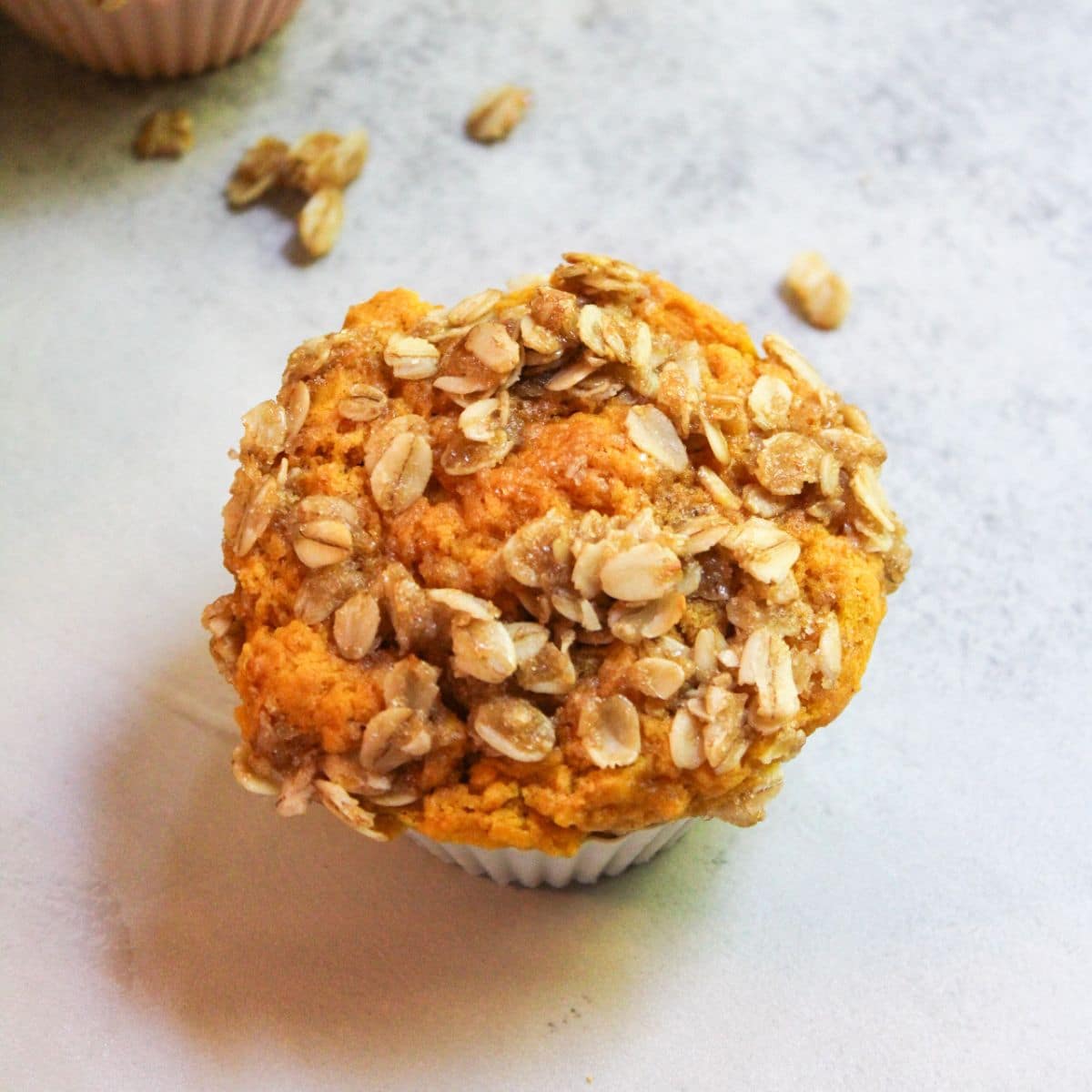 A sourdough pumpkin muffin that has a brown sugar streusel topping, in a white muffin liner