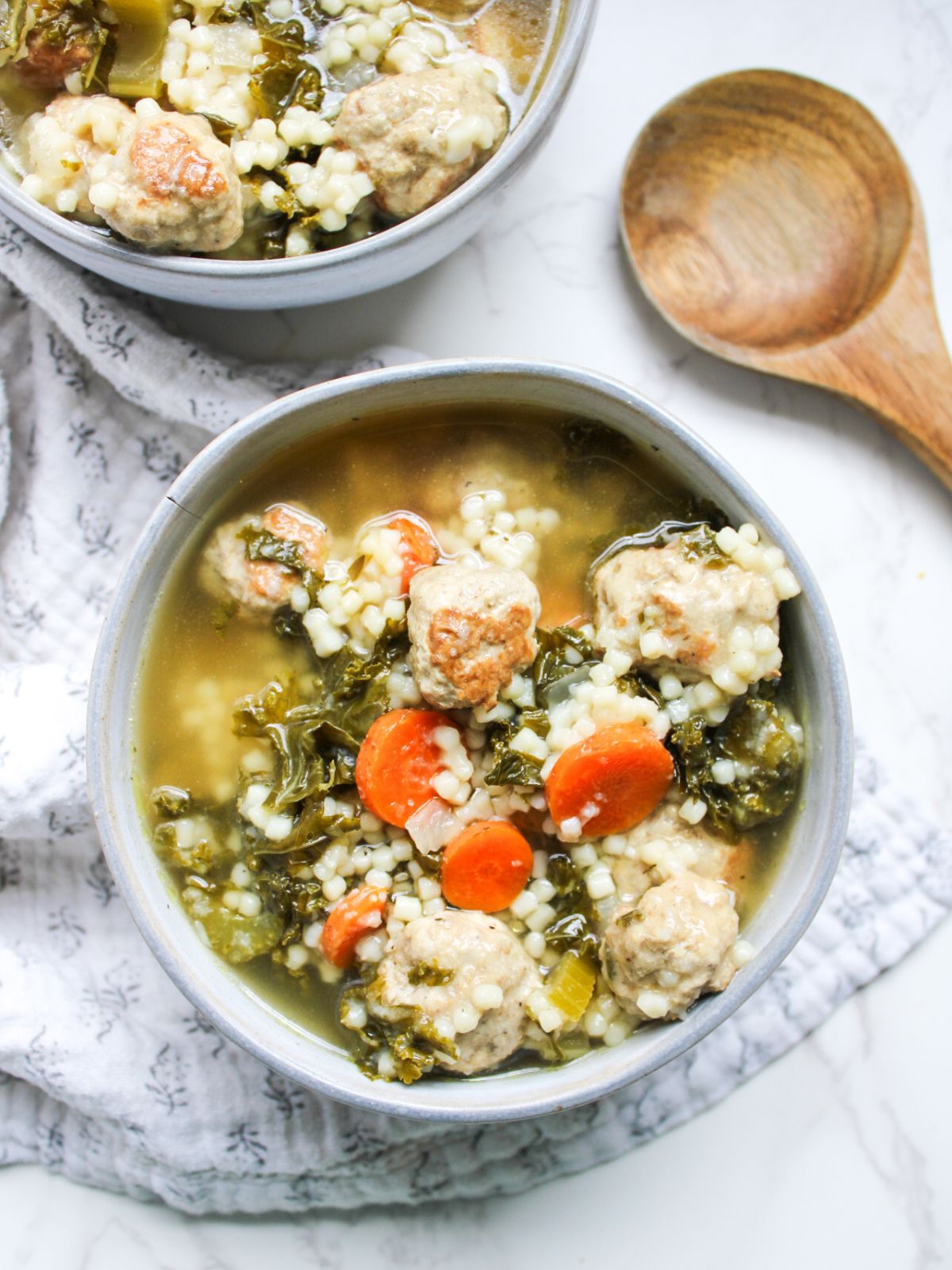 Two bowls of soup with a wooden ladle off to the side.