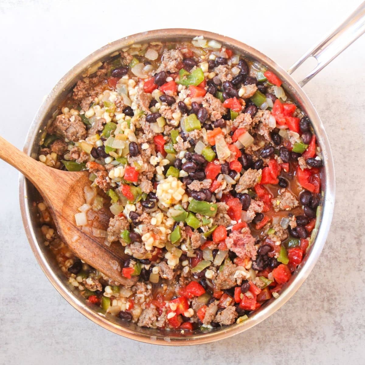 Add black beans, corn, diced tomatoes and chicken broth to the ground beef taco skillet.